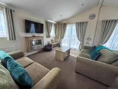 a living room with two couches and a tv at Stunning Lodge With Full Sea Views At Coopers Beach Holiday Park Ref 49019S in East Mersea
