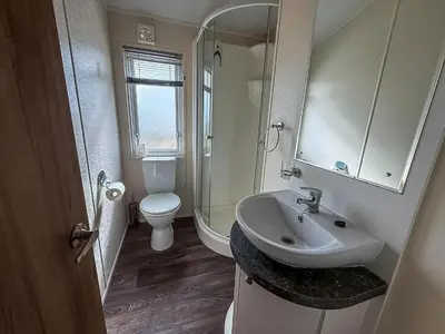 a bathroom with a sink and a toilet and a mirror at Stunning Lodge With Full Sea Views At Coopers Beach Holiday Park Ref 49019S in East Mersea