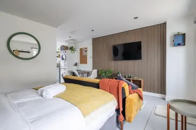 a bedroom with a bed and a tv on a wall at Modern Central Studio With Parking in Cambridge