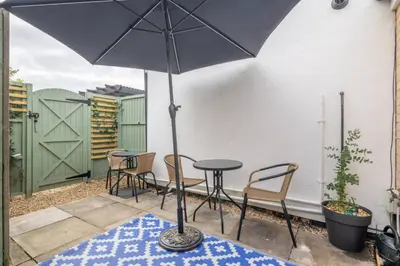 a patio with a table and chairs and an umbrella at Modern Central Studio With Parking in Cambridge