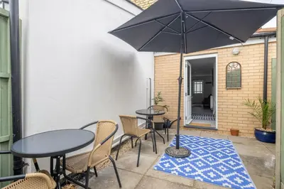 a patio with tables and chairs and an umbrella at Modern Central Studio With Parking in Cambridge