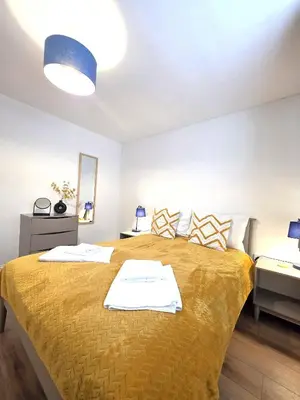 a bedroom with a bed with a yellow blanket at Deluxe One Bed Flat at Dawe Luxury Suites - An Entire Apartment near Ely Cathedral & Train Station - Ideal Gateway to Explore Ely, Cambridge, Norfolk & London - Sleeps up to 4 in Ely