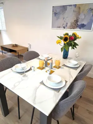 a white table with chairs and a vase of flowers at Deluxe One Bed Flat at Dawe Luxury Suites - An Entire Apartment near Ely Cathedral & Train Station - Ideal Gateway to Explore Ely, Cambridge, Norfolk & London - Sleeps up to 4 in Ely