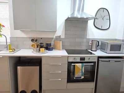 a kitchen with a stove and a clock on the wall at Cozy One Bed Flat at Dawe Luxury Suites - An Entire Apartment near Ely Cathedral & Train Station - The Perfect Base to Explore Ely, Cambridge, Norfolk & London - 2 Guests Max & Pet Friendly in Ely