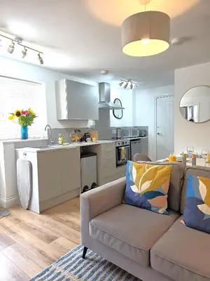 a living room with a couch and a kitchen at Cozy One Bed Flat at Dawe Luxury Suites - An Entire Apartment near Ely Cathedral & Train Station - The Perfect Base to Explore Ely, Cambridge, Norfolk & London - 2 Guests Max & Pet Friendly in Ely