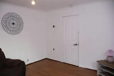 an empty living room with a white wall and a door at Homely three bedroom in Vange