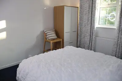 a bedroom with a bed and a chair and a window at Homely three bedroom in Vange