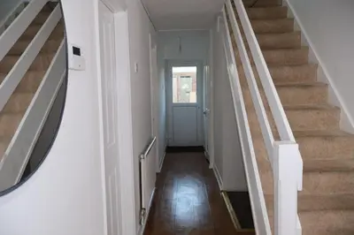 a hallway with stairs and a mirror on the wall at Homely three bedroom in Vange