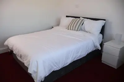 a white bed with a black headboard and white pillows at Homely three bedroom in Vange