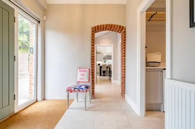 a hallway with a chair and a mirror at Coach House with Hot Tub in Idyllic Bury St Edmunds in Newton