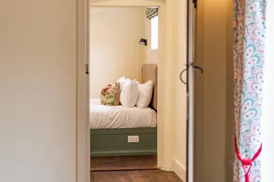 a bedroom with a bed with white sheets and pillows at Coach House with Hot Tub in Idyllic Bury St Edmunds in Newton