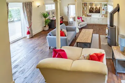 a living room with a couch and a table at Coach House with Hot Tub in Idyllic Bury St Edmunds in Newton