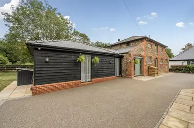 a house with a black garage and a brick building at Coach House with Hot Tub in Idyllic Bury St Edmunds in Newton