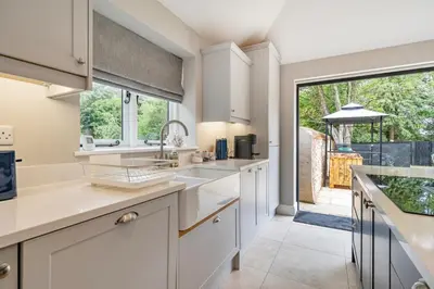 a kitchen with white cabinets and a large window at Coach House with Hot Tub in Idyllic Bury St Edmunds in Newton