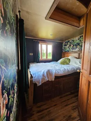a bedroom with a bed in a room with a window at offgrid showmans caravan in Kelvedon Hatch