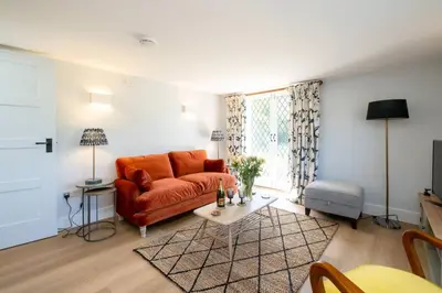a living room with an orange couch and a table at Rose Cottage, Blaxhall - Near Snape Maltings, Orford, Thorpeness & Aldeburgh - Aldeburgh Coastal Cottages in Blaxhall