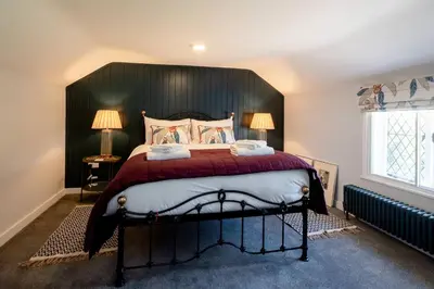 a bedroom with a large bed with a black headboard at Rose Cottage, Blaxhall - Near Snape Maltings, Orford, Thorpeness & Aldeburgh - Aldeburgh Coastal Cottages in Blaxhall