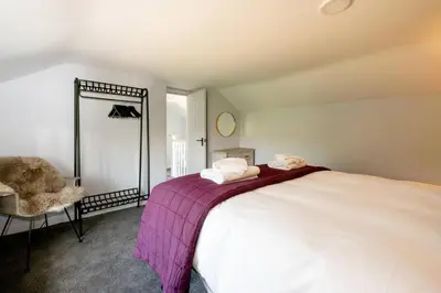 a bedroom with a bed and a mirror and a chair at Rose Cottage, Blaxhall - Near Snape Maltings, Orford, Thorpeness & Aldeburgh - Aldeburgh Coastal Cottages in Blaxhall