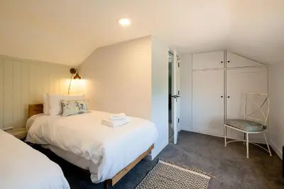 a bedroom with a white bed and a chair at Rose Cottage, Blaxhall - Near Snape Maltings, Orford, Thorpeness & Aldeburgh - Aldeburgh Coastal Cottages in Blaxhall