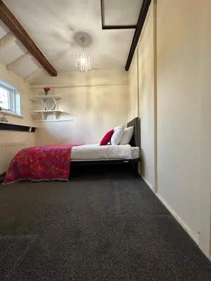 a bedroom with a bed in the corner of a room at Rosemary cottage in Mountnessing