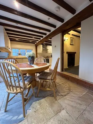 a kitchen and dining room with a wooden table and chairs at Rosemary cottage in Mountnessing