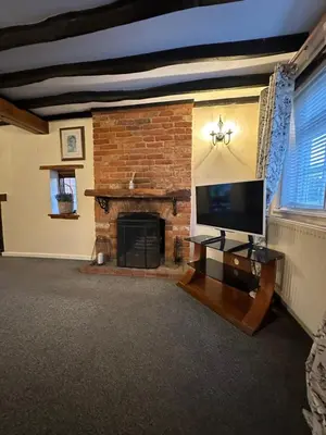 a living room with a fireplace and a flat screen tv at Rosemary cottage in Mountnessing