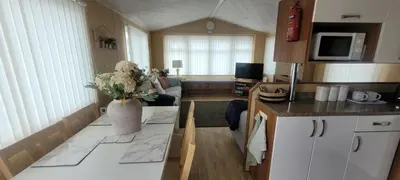 a kitchen and living room with a vase of flowers on a counter at Willerby Delux - Holiday Home by the Sea - close to the Entertainment Complex-bedding, towels & wifi Included! in Jaywick Sands