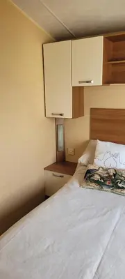 a bedroom with a bed with white sheets and cabinets at Willerby Delux - Holiday Home by the Sea - close to the Entertainment Complex-bedding, towels & wifi Included! in Jaywick Sands
