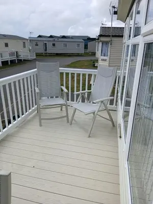 two chairs on a deck with houses in the background at Willerby Delux - Holiday Home by the Sea - close to the Entertainment Complex-bedding, towels & wifi Included! in Jaywick Sands