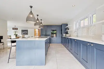 a kitchen with blue cabinets and a large island at Mayrose House - 6BR 4BATH Luxe Spacious Retreat in Takeley