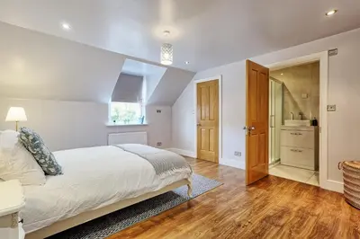 a bedroom with a large bed and a bathroom at Mayrose House - 6BR 4BATH Luxe Spacious Retreat in Takeley