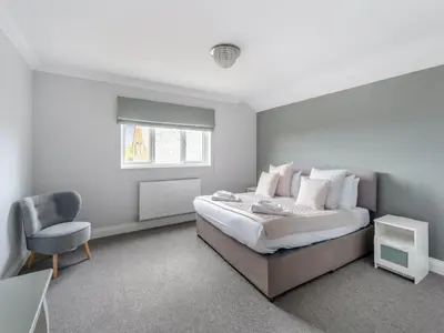 a bedroom with a bed and a chair and a window at Mals Barn in Althorne