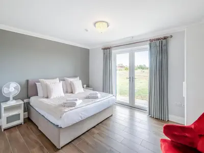 a white bedroom with a bed and a window at Mals Barn in Althorne
