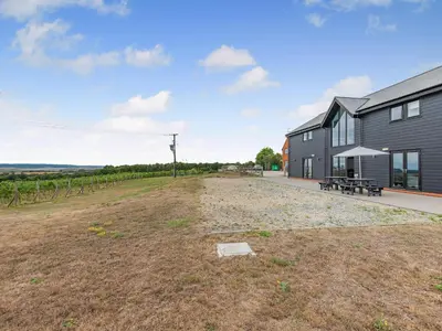 an empty field in front of a building with a bench at Mals Barn in Althorne