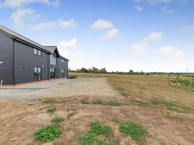 an empty field next to a black barn at Mals Barn in Althorne