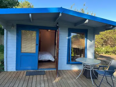 a small house with a blue door and a table on a deck at Double bedroom cabin suffolk in Martlesham