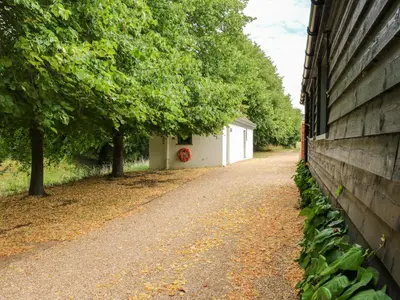 a dirt road next to a building with trees at Clock Tower in Stowmarket