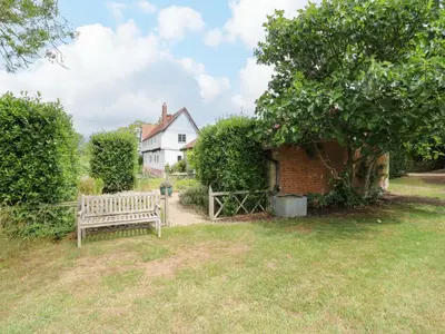 a wooden bench sitting in the grass in front of a house at Clock Tower in Stowmarket