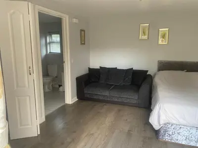 a bedroom with a couch and a bed and a bathroom at Latchmead in Little Hallingbury