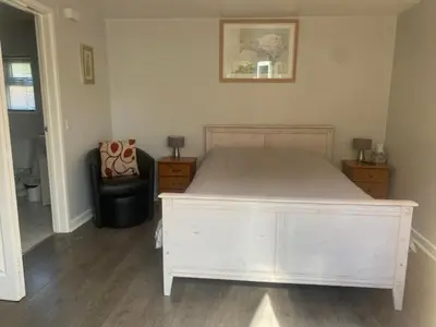 a bedroom with a white bed and a chair at Latchmead in Little Hallingbury