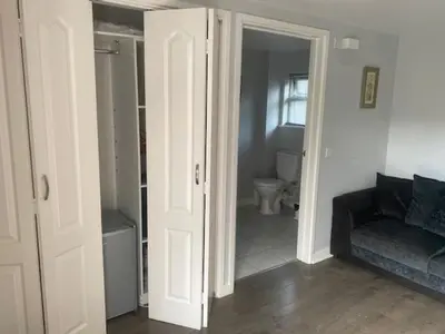a living room with a couch and a bathroom at Latchmead in Little Hallingbury