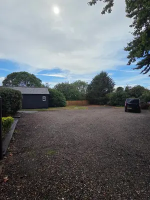 a parking lot with a car parked in a driveway at Latchmead in Little Hallingbury