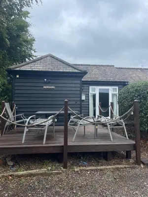 two chairs sitting on a wooden deck in front of a house at Latchmead in Little Hallingbury
