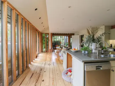 a kitchen with wooden flooring and a hallway with windows at Headland Barn in Maldon