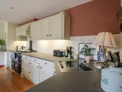 a kitchen with white cabinets and a counter top at Headland Barn in Maldon