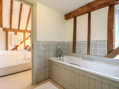a bathroom with a tub next to a bed at Headland Barn in Maldon