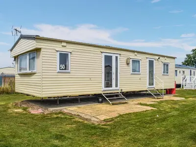 a small yellow house on a yard at Praise Machine Caravan Experience in Jaywick Sands