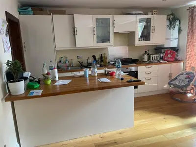 a kitchen with white cabinets and a wooden counter top at Konesha in Loughton