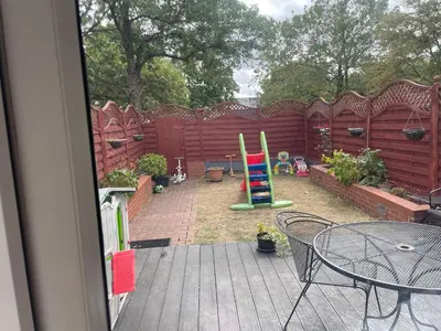 a patio with a table and chairs and a fence at Konesha in Loughton
