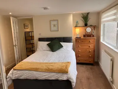 a bedroom with a bed and a dresser and a window at The Cosy Annexe in Wymondham